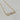 A gold chain necklace with a bar pendant featuring a rectangular stone, a round clear stone, a heart-shaped clear stone, and another rectangular stone.