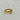 A gold ring with a rough, organic-shaped bezel holding a clear oval gemstone.