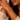 A close-up lifestyle shot of a woman wearing a gold twisted cable bracelet with sculptural hook-and-loop closure and sparkling crystal accents, styled with a cream knit sweater.