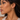 A model wearing a pair of gold hoop earrings with a textured, diamond-like paved edge.