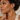 A model wearing a pair of gold hoop earrings with a textured, diamond-like paved edge.