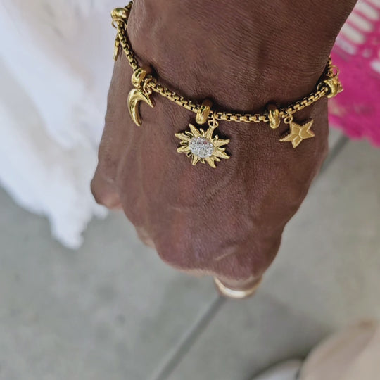 Multiple charms statement bracelet with a sun, stars, and moon.  Available in 18kt gold plating over stainless steel or silver tone stainless steel. Great for layering with other bracelets.