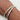 Two slim bangle bracelets with baguette-cut clear stones, one in yellow gold and one in silver, worn on a person's wrist against a light background.
