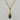 A gold chain necklace with a marquise-shaped pendant featuring a brown and gold tiger's eye stone, set against a light gray marble background.