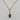 A gold chain necklace with a marquise-shaped pendant featuring a green jade gemstone, set against a light gray marble background.