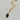 A gold chain necklace with a marquise-shaped pendant featuring a black and gold black obsidian gemstone, set against a light gray marble background.