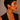 A close up of a model wearing A pair of small gold hoop earrings with a glossy black curved inlay design
