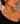A model wearing a gold chain necklace with a marquise-shaped pendant featuring a brown and gold tiger's eye stone.